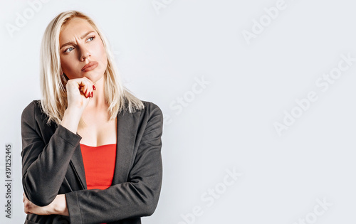 Beautiful young girl unhappy frown and thinks on gray isolated background
