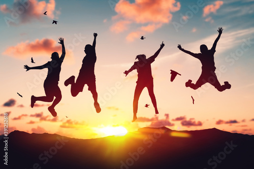 Silhouette friends jump and birds fly on sunset sky at top of mountain abstract background. © tonktiti