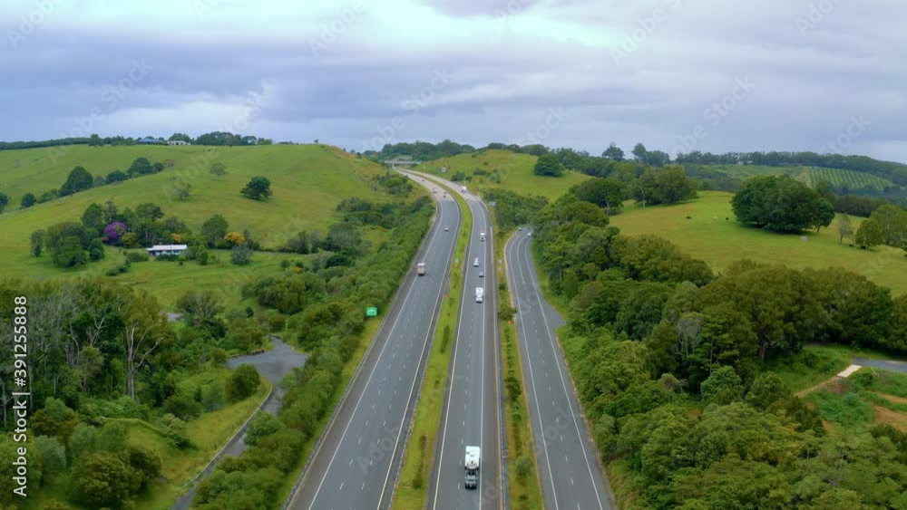 Vehicles Driving On The Uphill Carriageways Surrounded By Green Landscape In Byron Bay, NSW, Australia. - aerial drone shot Vehicles Driving On The Uphill Carriageways Surrounded By Green Landscape In Byron Bay, NSW, Australia. - aerial drone shot