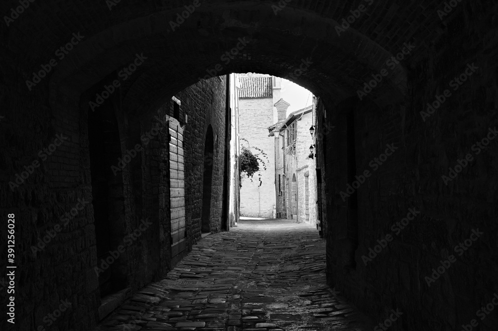 The view of an ancient alley under an architectural arch in a medieval Italian village (Gubbio, Umbria, Italy)