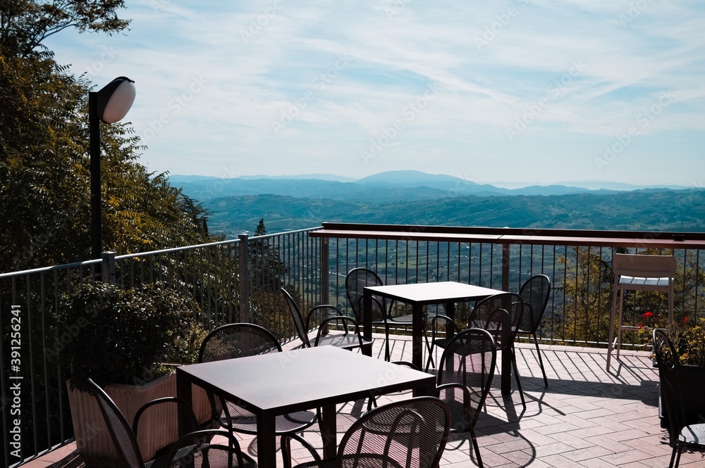 Tables and chairs on a terrace of a bar with a panoramic view (Gubbio, Umbria, Italy)