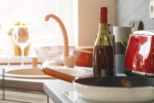 Bottle of red wine, frying pan near the sink on countertop