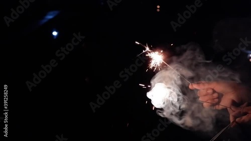 Slow video clip of a yellow scab splashing from fireworks in hand  and white smoke floating on a black background.