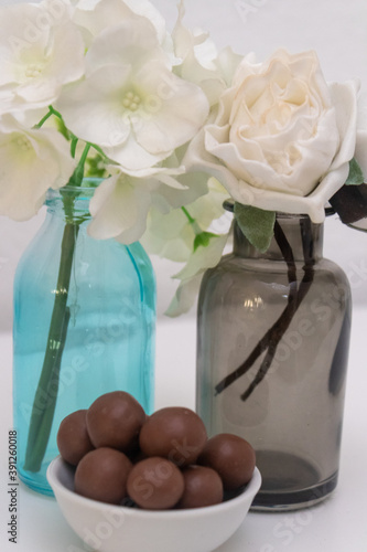 Decorative flowers in a blue and a gray vase with truffles in the foreground