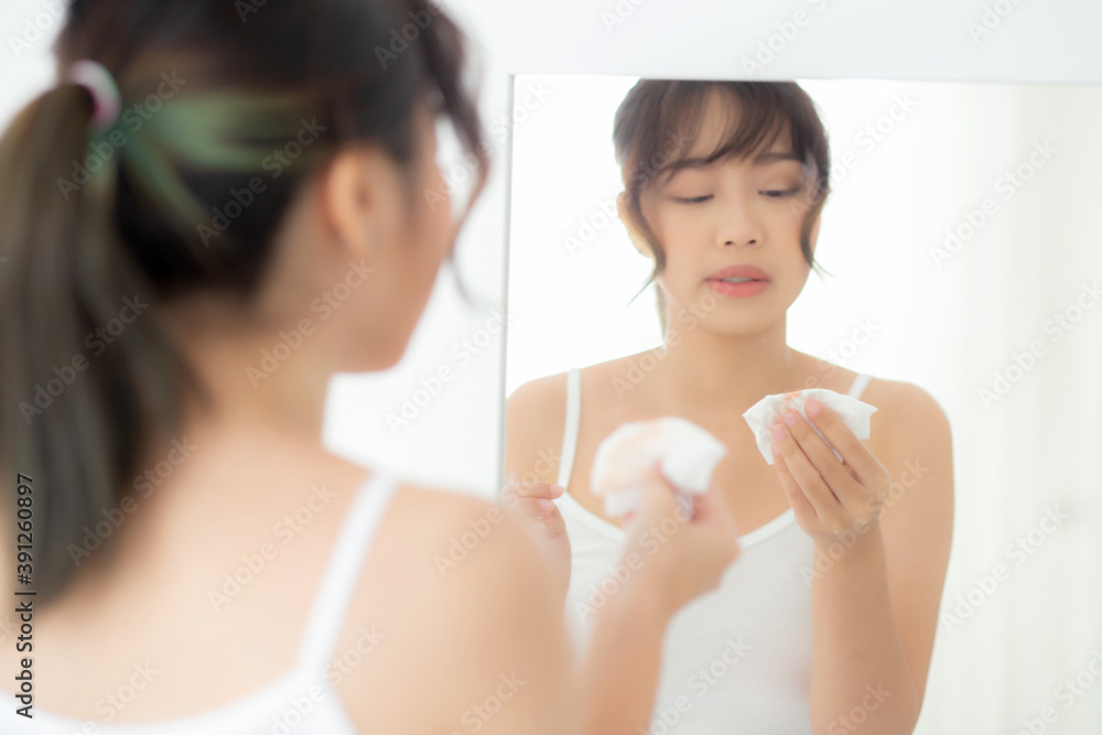 Beautiful young asian woman smiling with skin care cosmetic use oil blotting paper on face looking mirror at room, beauty asia girl wipe and cleansing makeup with tissue, clean on facial concept. Beautiful young asian woman smiling with skin care cosmetic use oil blotting paper on face looking mirror at room, beauty asia girl wipe and cleansing makeup with tissue, clean on facial concept.
