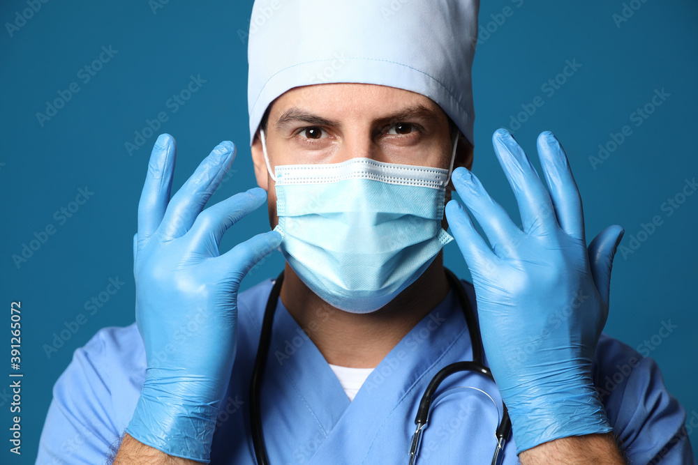 Doctor in protective mask and medical gloves against blue background Doctor in protective mask and medical gloves against blue background