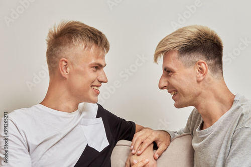 Happy gay couple spend time together, talking and smiling, holding hands, looking at each other. © Evgenia