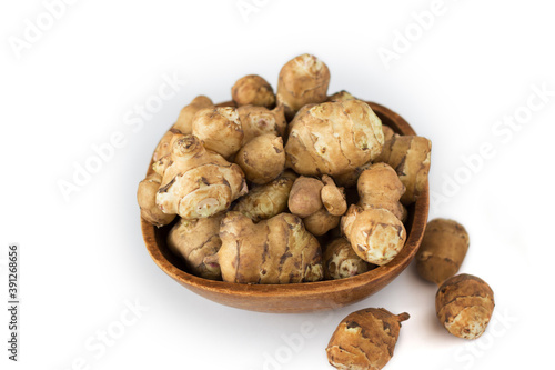 Jerusalem artichoke in brown wooden bowl, isolated, close up, top view