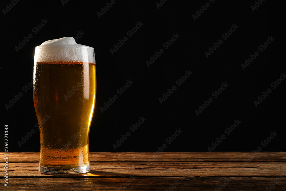 Cold tasty beer on wooden table against dark background. Space for text