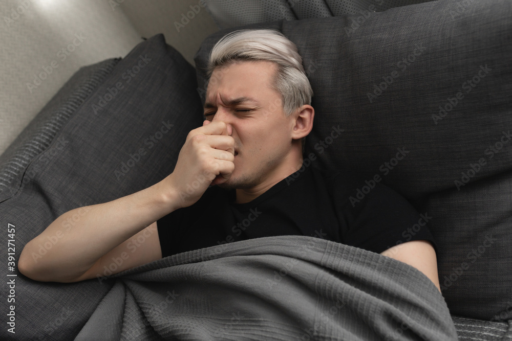 Man with white hair is sick while lying on the sofa at home Man with white hair is sick while lying on the sofa at home