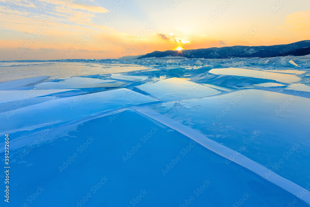 Obraz premium Transparent blue hummocks Baikal ice is shining through the crack sunset