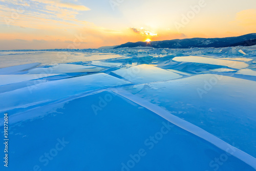 Transparent blue hummocks Baikal ice is shining through the crack sunset © Baikal360