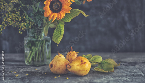 Autumn still life with flowers, leaves and fruit on the dark background.