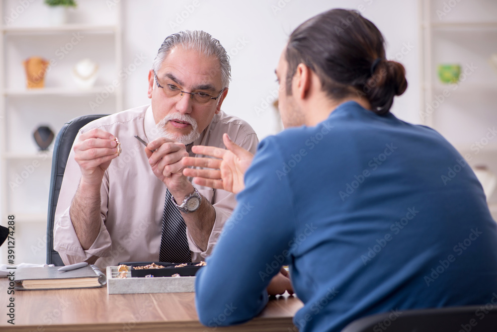 Young man visiting old male jeweler Young man visiting old male jeweler