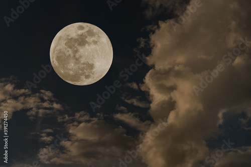 Full moon over clouds on the sky.