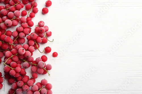 Tasty frozen red currants on white wooden table, flat lay. Space for text
