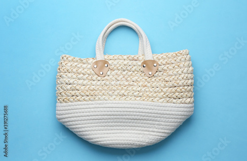 Elegant woman's straw bag on light blue background, top view