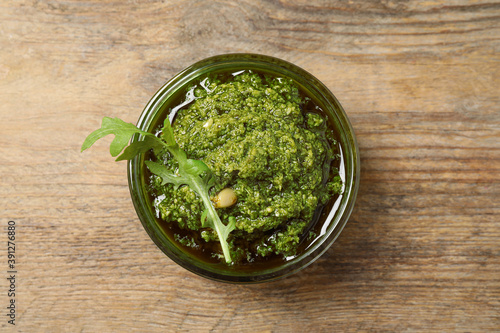 Bowl of tasty arugula pesto on wooden table, top view