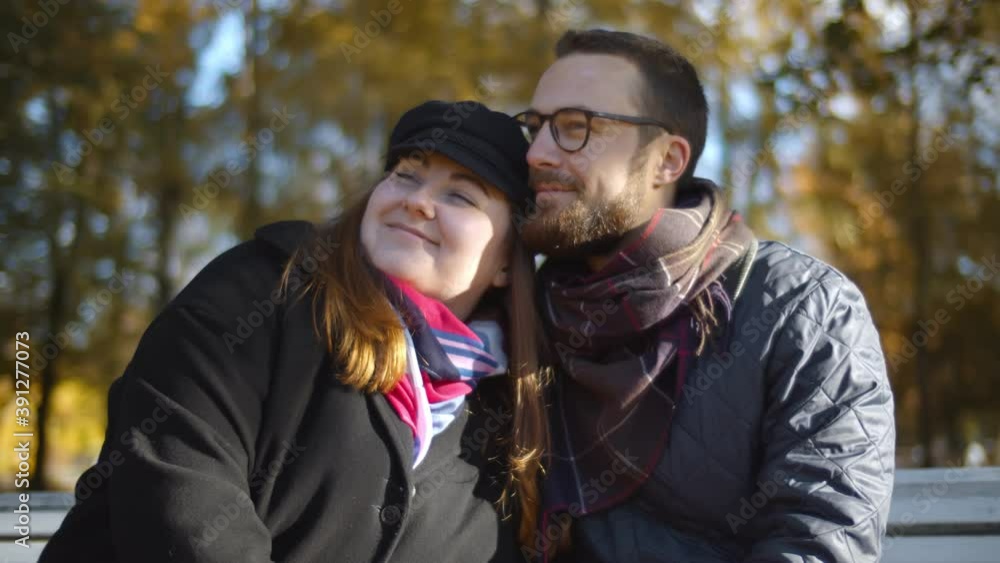 Young happy couple having date embracing on bench in autumn park. Young happy couple having date embracing on bench in autumn park.