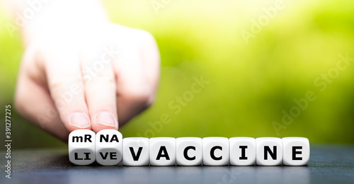 Hand turns dice and changes the expression "live vaccine" to "mRNA vaccine".
