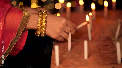 Indian woman or newly wed bride lights up the candles on Diwali night at home. Concept for festive celebration, Hindu religious culture, tradition, rituals.