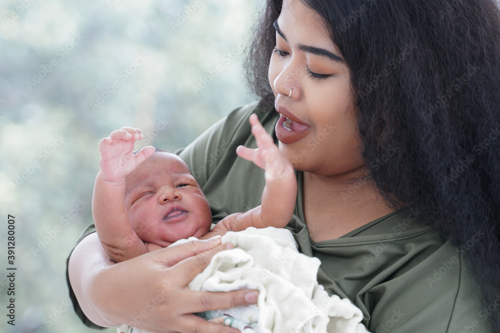 Portrait of African mom carrying adorable newborn baby in her arm. Happy lovely African American family mother and son at bedroom Portrait of African mom carrying adorable newborn baby in her arm. Happy lovely African American family mother and son at bedroom