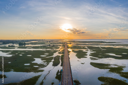 Aerial view of highway during sunrise in the middle of  swamp