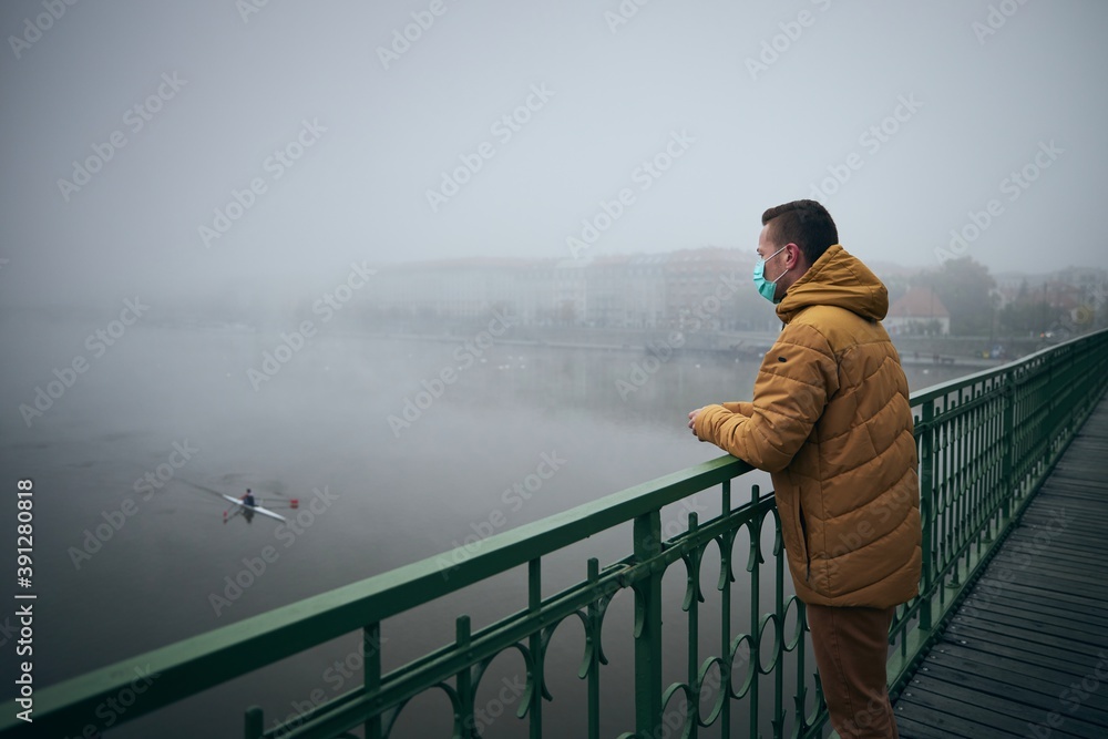 Lonely man wearing face mask against city in fog