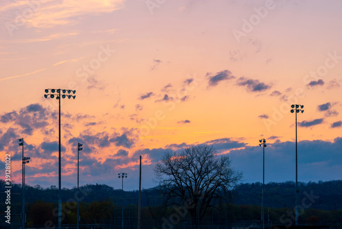 Landscape sunset or sunrise with silhouette of poles or column of spotlight or stadium light in arena with mountain and beautiful sky cloud and with copy space.