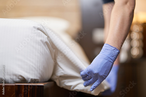 Female hands holding white sheet and making the bed