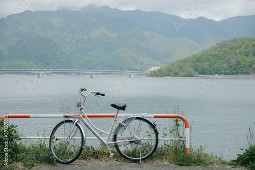 The bicycle is parked by the lake with the bridge and mountains in the background. Kawaguchi lake, Japan 