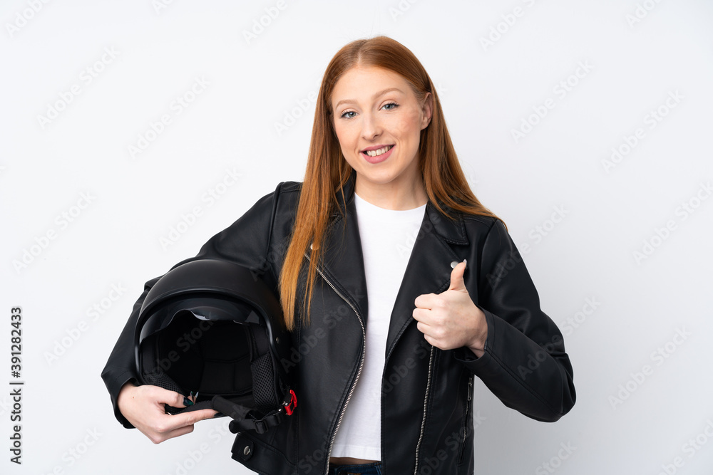 Young redhead woman with a motorcycle helmet over isolated white background with thumbs up because something good has happened Young redhead woman with a motorcycle helmet over isolated white background with thumbs up because something good has happened