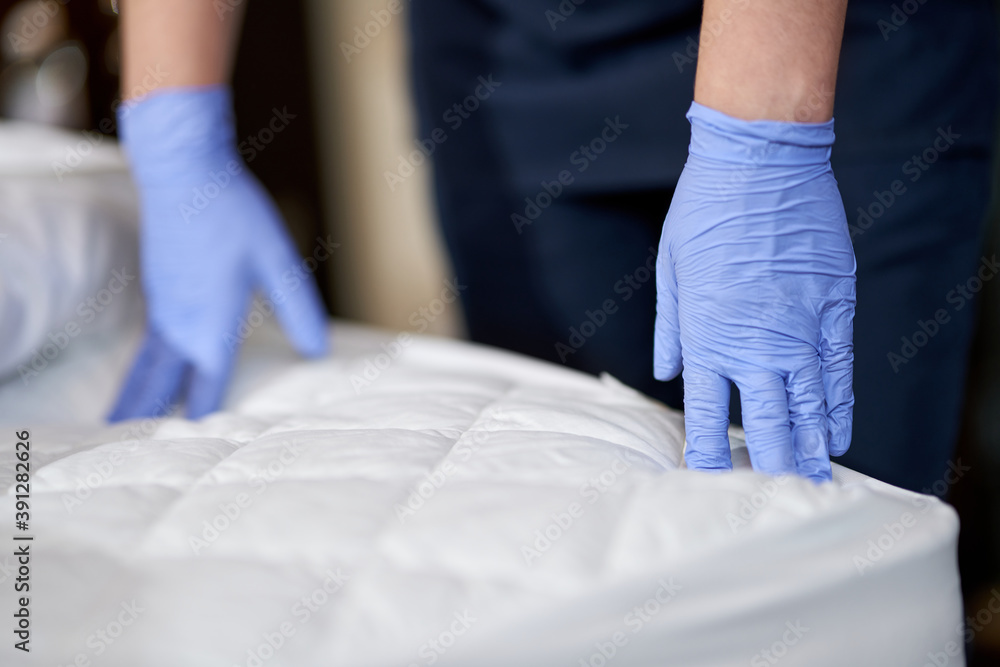 Maid in gloves touching the mattress by hands Maid in gloves touching the mattress by hands