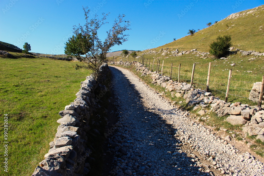 Large stones stacked in the wall to fence off the field from the road. Road to the old Bosnian village of Lukomir.