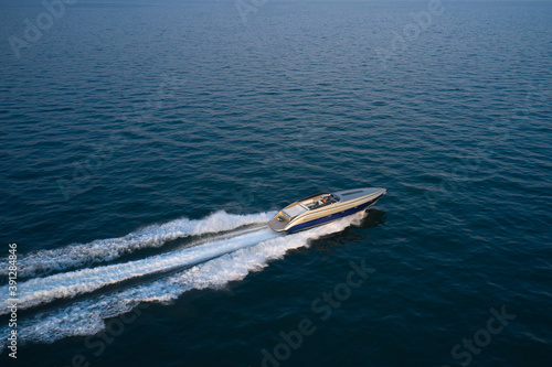 Large speedboat moving at high speed. The boat is gray-blue combined color. Large speed boat moving at high speed side view.