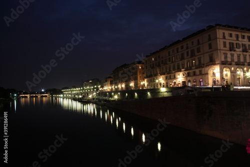 View of riverbank and bridge crossing over the PO river at night in Turin, Italy.