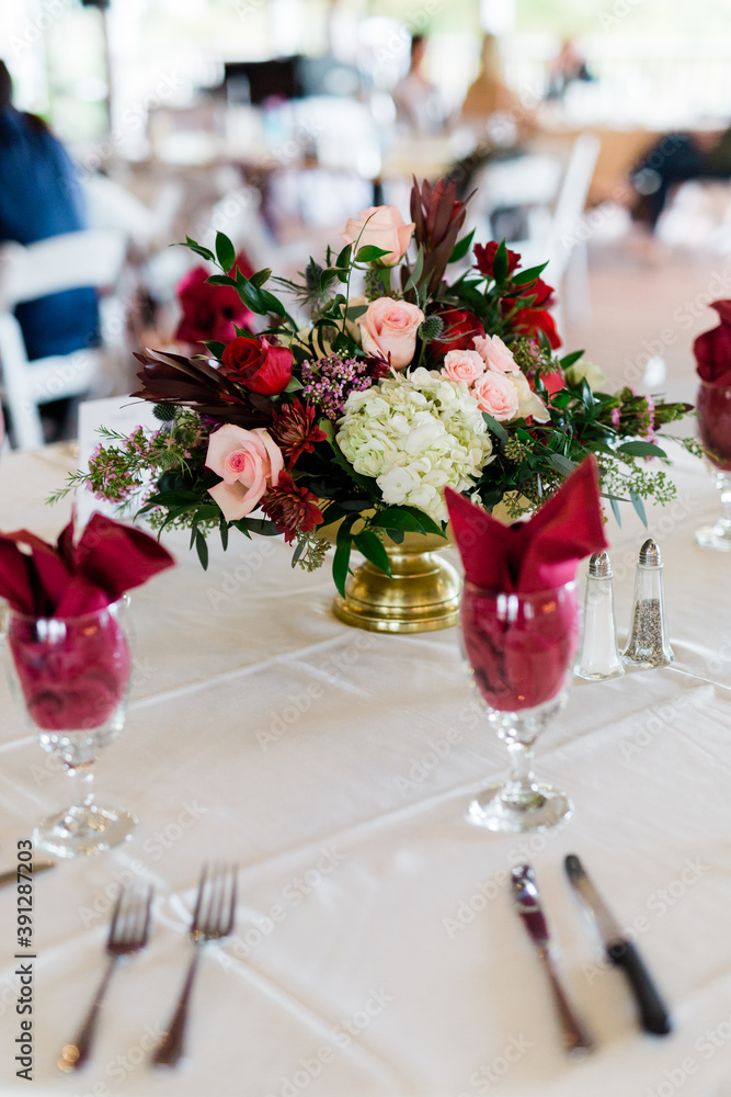 Beautiful Flower Centerpiece in Reds and Dark Colors for a Holiday Wedding, Red Napkins in Wine Glasses Beautiful Flower Centerpiece in Reds and Dark Colors for a Holiday Wedding, Red Napkins in Wine Glasses