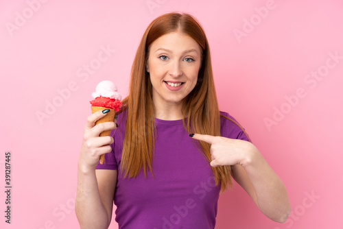 Young redhead woman with a cornet ice cream over isolated pink background with surprise facial expression