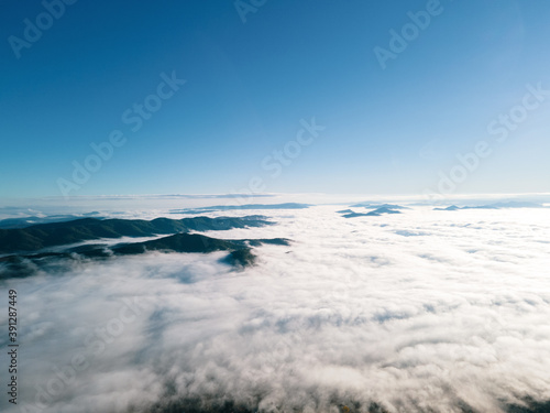 Aerial of mountain peaks above the white clouds.