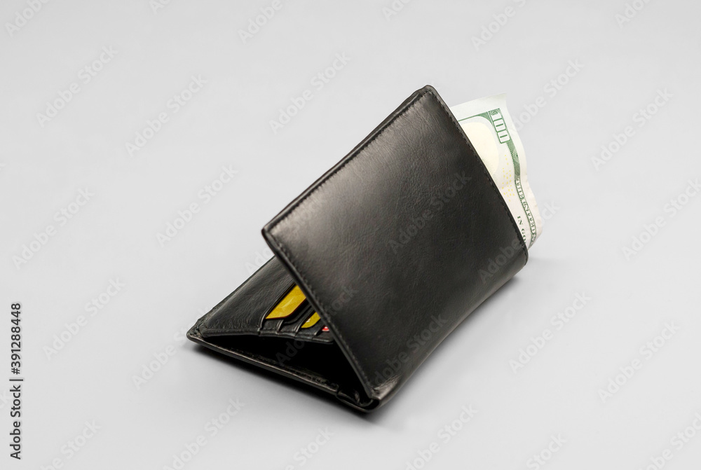 Wallet with a hundred dollar bill and credit cards on a gray background Wallet with a hundred dollar bill and credit cards on a gray background