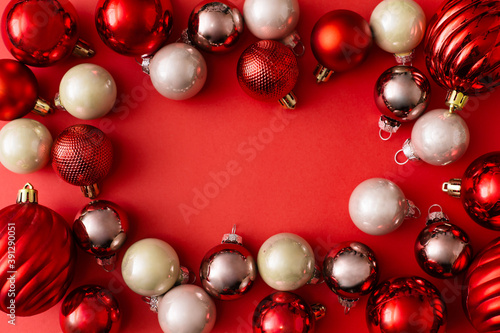 Christmas colourful balls decoration and tree branches on red background. New Year greeting card. Minimal style. Flat lay, top view, copy space.
