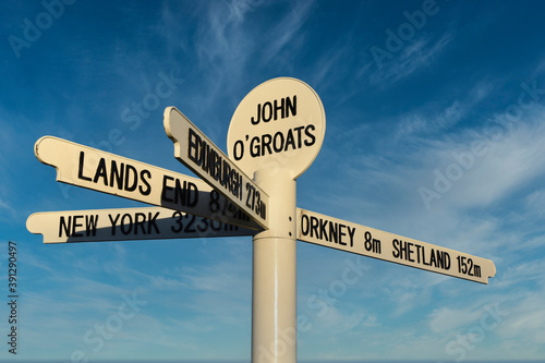 New John O'Groats signpost on NC500 route with blue sky and light cloud background. Mileage to Orkney, Shetland, Lands End, Edinburgh and New York. Famous spot for tourists to get photographs taken. photo