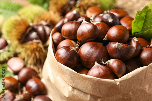 Fresh sweet edible chestnuts in paper bag, closeup