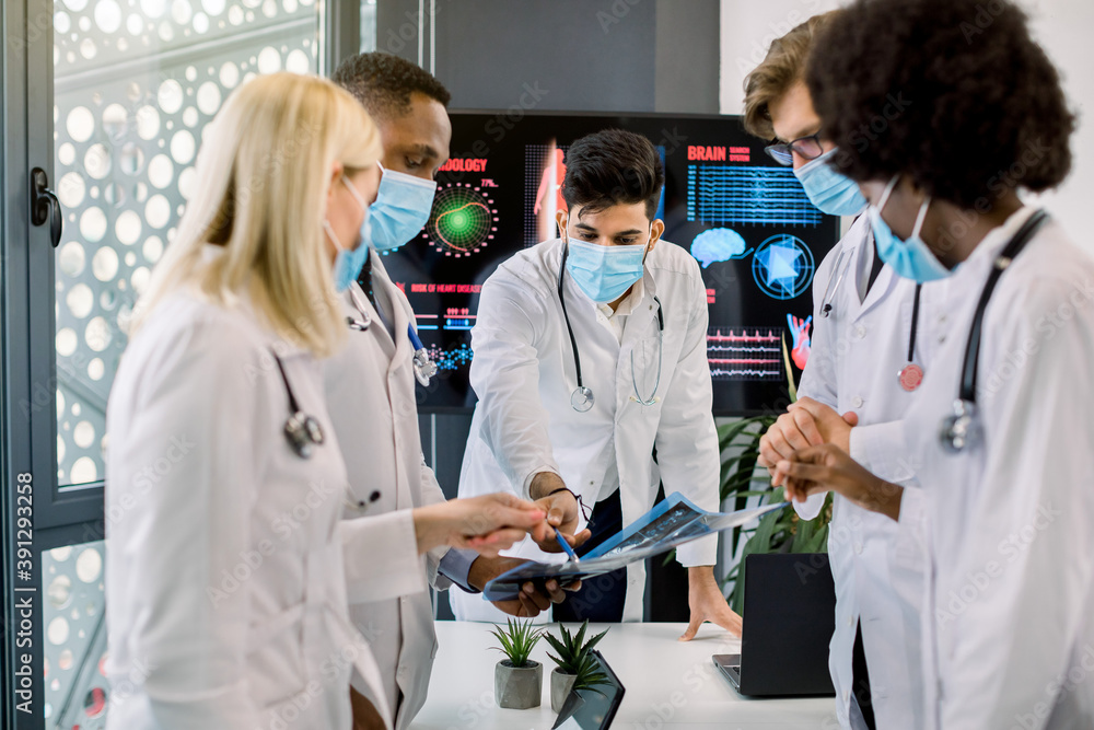Multiracial doctors wearing protective masks, examining patient's ct scan of chest and abdominal cavity. Pulmonology, lung pathology, inflammatory diseases, tuberculosis diagnostics concept Multiracial doctors wearing protective masks, examining patient's ct scan of chest and abdominal cavity. Pulmonology, lung pathology, inflammatory diseases, tuberculosis diagnostics concept