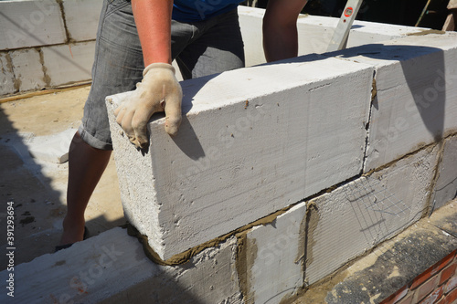 A building contractor is building a wall lying autoclaved aerated concrete (AAC) blocks over brick foundation with bitumen asphalt waterproofing membrane installed. photo