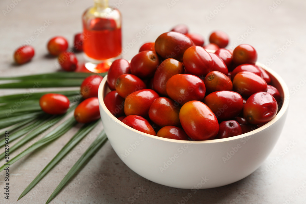 Palm oil fruits in bowl on grey table, closeup Palm oil fruits in bowl on grey table, closeup