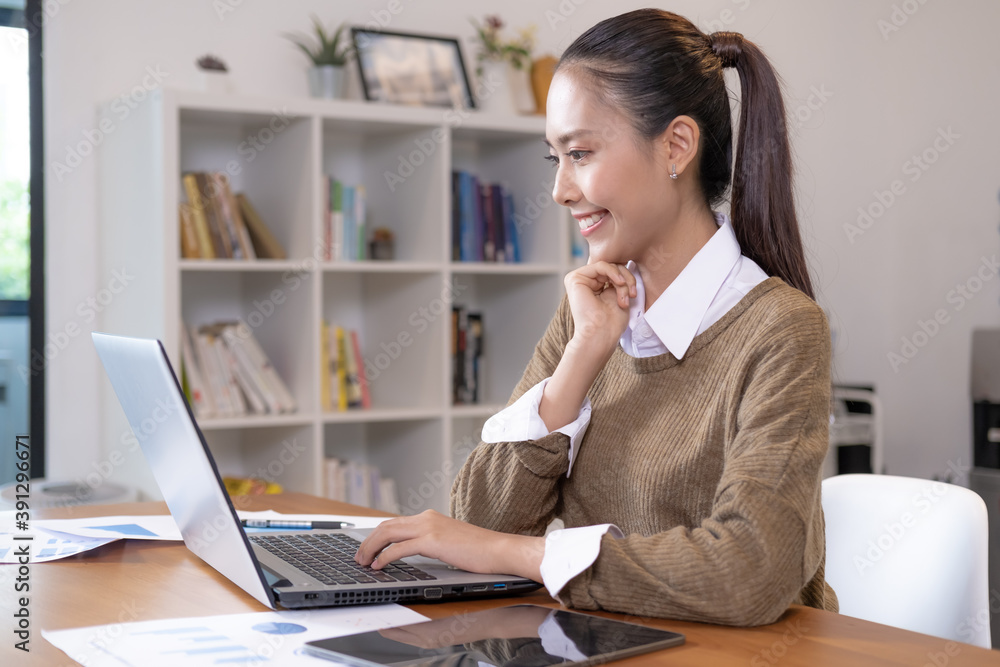 Young asian businesswoman working with her laptop. She smiled and sitting happily at work. Young asian businesswoman working with her laptop. She smiled and sitting happily at work.