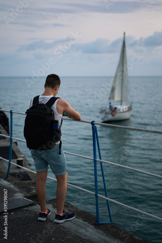 A man on the embankment on the background of a boat