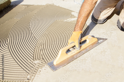 worker applying tile adhesive glue on the floor
 photo