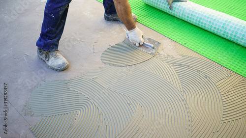 worker applying tile adhesive glue on the floor
 photo